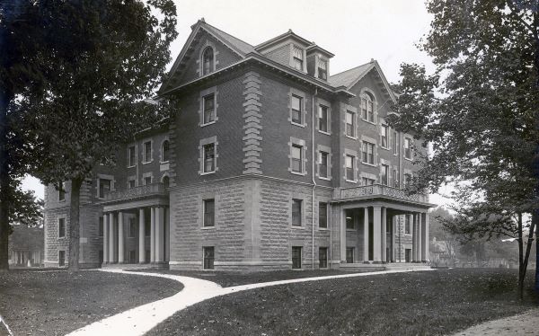 A black and white photo of Cochran Hall in 1921. It is a tall, old-fashioned building made of brick and stone.