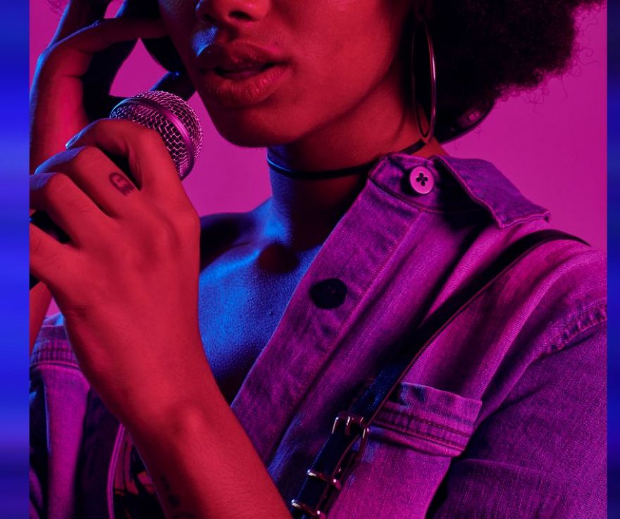 A hazy laser lit photo of a Black woman speaking into a microphone
