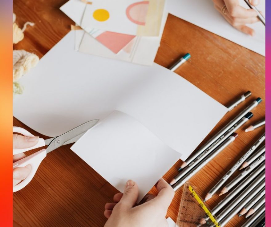 A rainbow background; overlaid is a picture of someone cutting out a square from a larger sheet of paper, with pencils and other art supplies scattered around.
