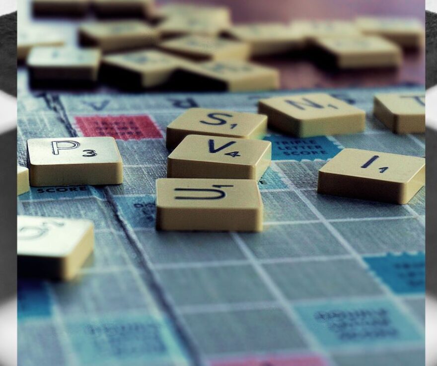 A closeup picture of a Scrabble board, with letter tiles scattered across the board.